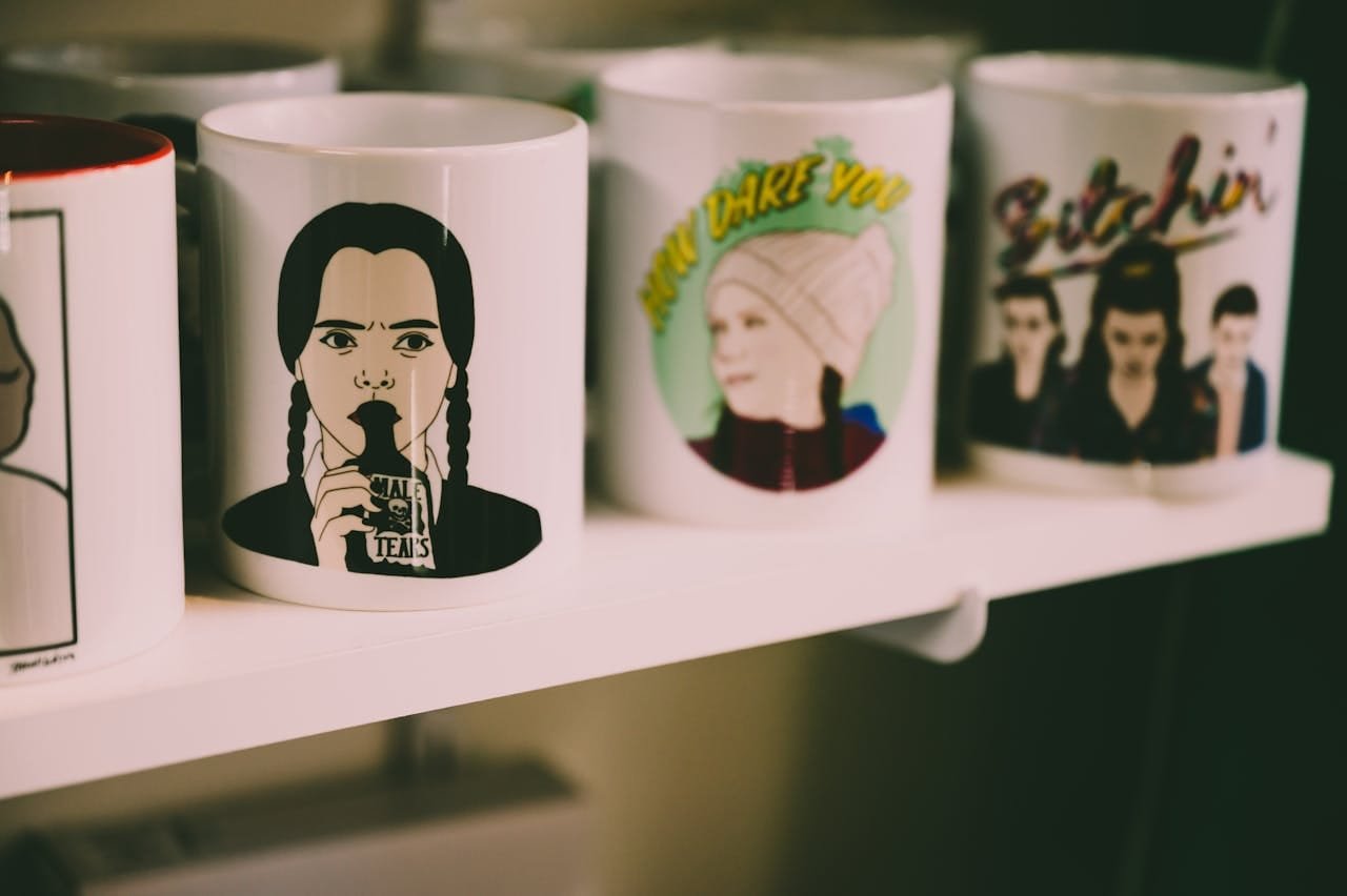 A collection of artistic ceramic mugs featuring graphic designs displayed on a shelf.